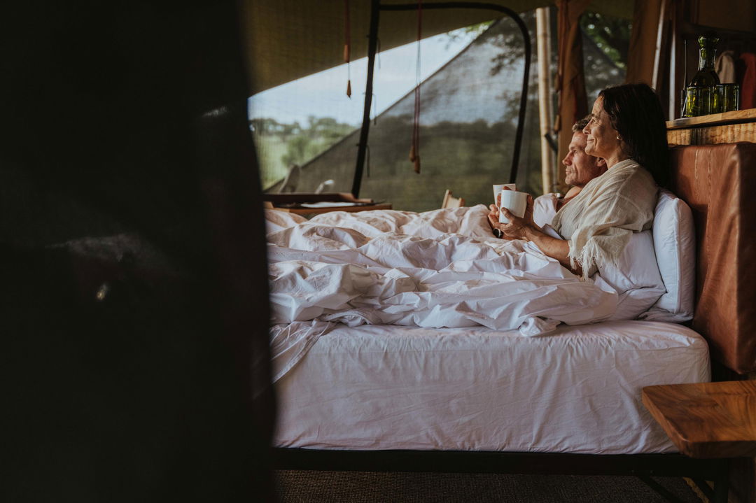 couple having coffee in bed by Wilderness Usawa tented camp Serengeti