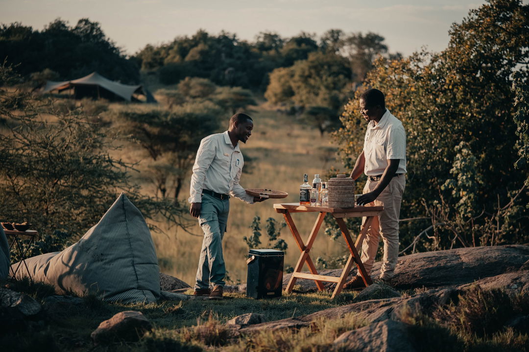 two staff setting up sundowners table by Wilderness Usawa tented camp Serengeti