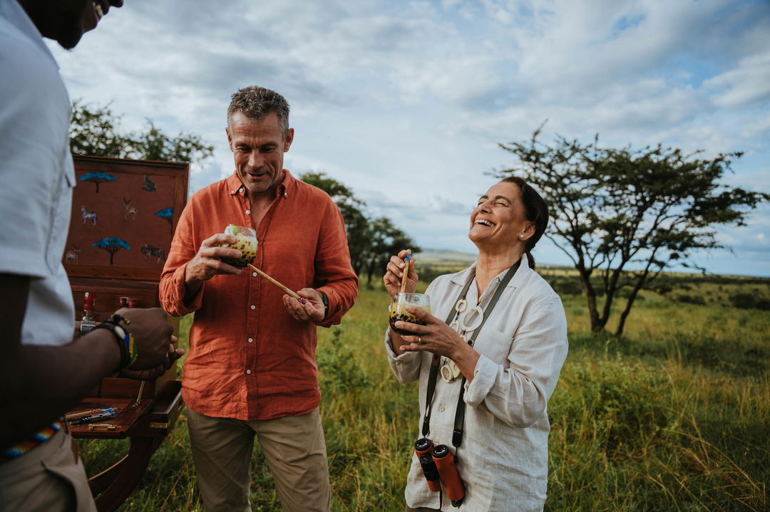 couple enjoying sundowners by Wilderness Usawa tented camp Serengeti