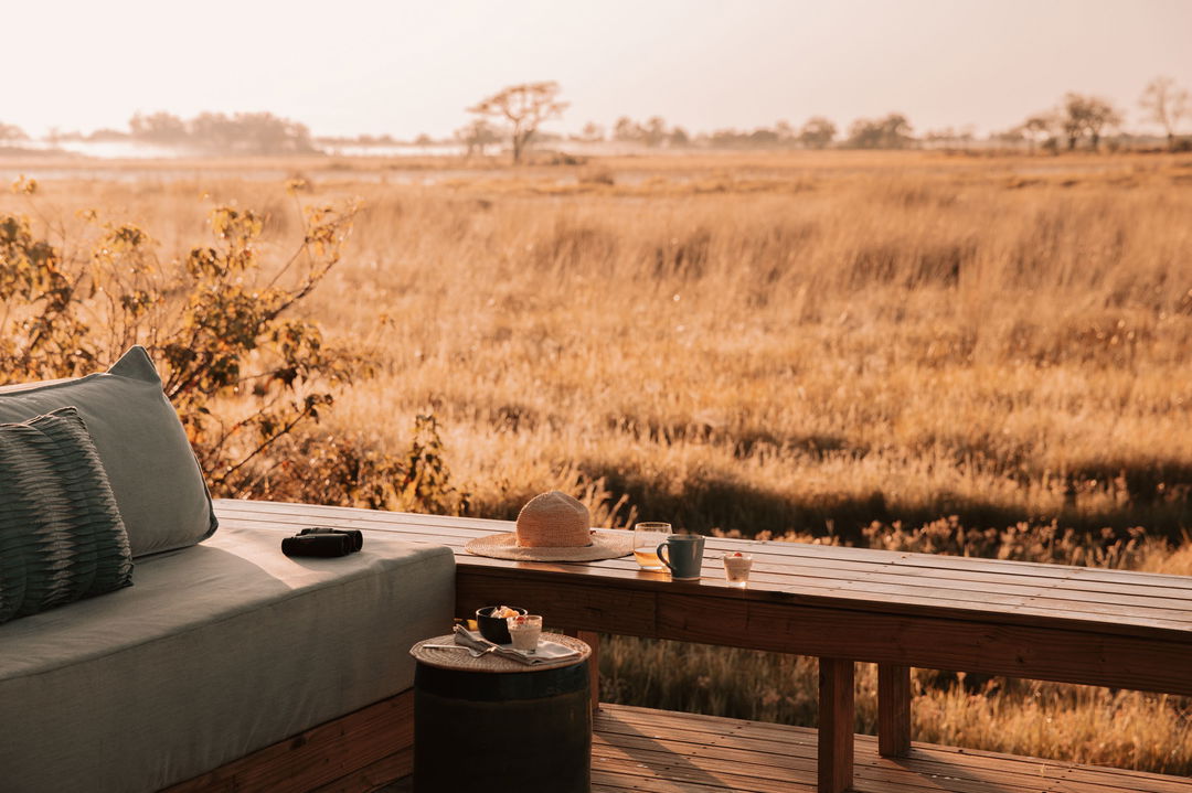 viewing deck with safari hat and glass with delta in backdrop at Vumbura Plains Camp Wilderness Okavango Delta