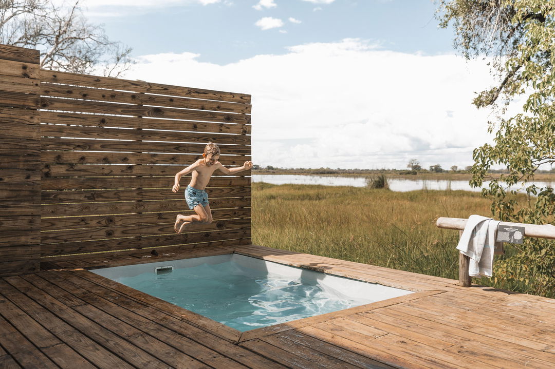 kid jumping into splash pool on room deck at Vumbura Plains Camp Wilderness Okavango Delta