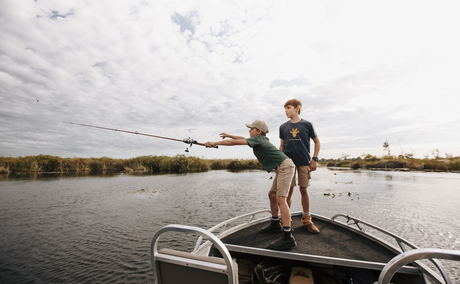 two young boys fishing from boat in delta at Vumbura Plains Camp Wilderness Okavango Delta two young boys fishing from boat in delta at Vumbura Plains Camp Wilderness Okavango Delta