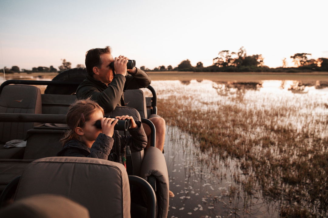guests with binoculars looking at water plains of Vumbura Plains Camp Wilderness Oka