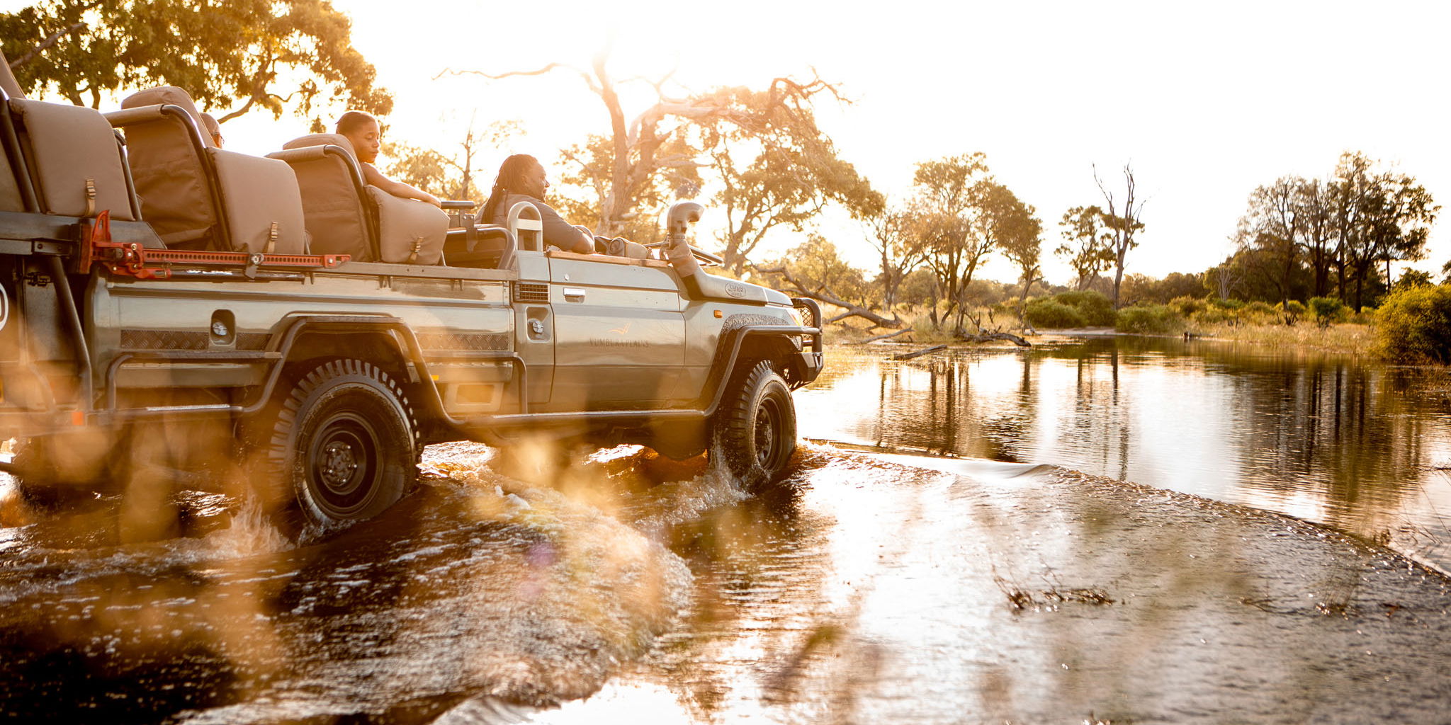 safari vehicle driving through delta water at Vumbura Plains Camp Wilderness Okavango Delta
