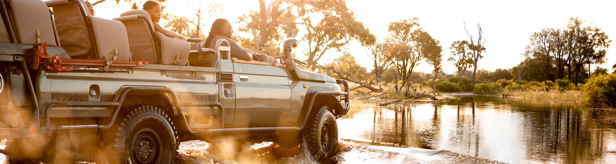 safari vehicle driving through delta water at Vumbura Plains Camp Wilderness Okavango Delta