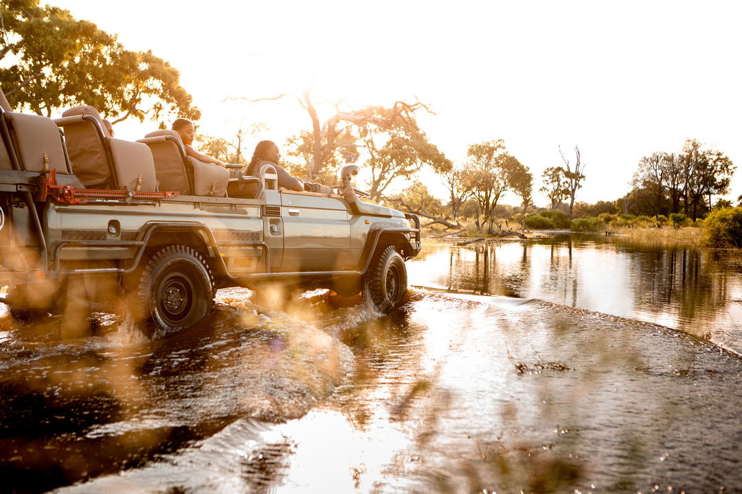 safari vehicle driving through delta water at Vumbura Plains Camp Wilderness Okavango Delta