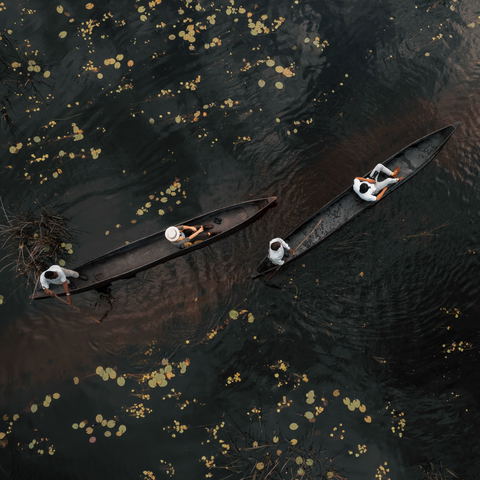 two black mokoros in black water with guests filmed from above at Vumbura Plains Camp Wilderness Okavango Delta