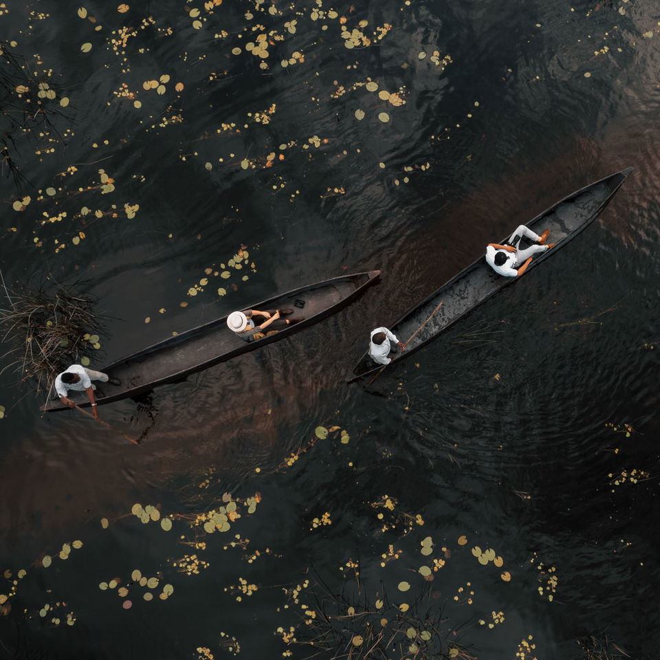 two black mokoros in black water with guests filmed from above at Vumbura Plains Camp Wilderness Okavango Delta
