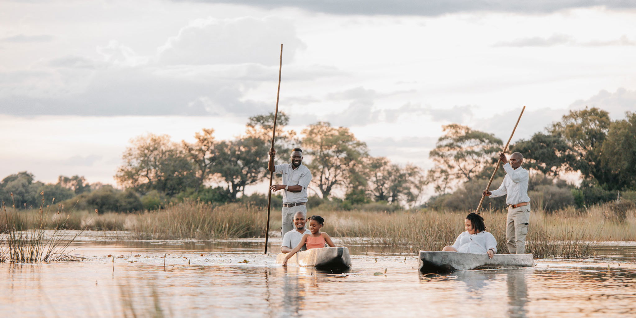 guests and guides in mokoros floating on delta at Vumbura Plains Camp Wilderness Okavango Delta