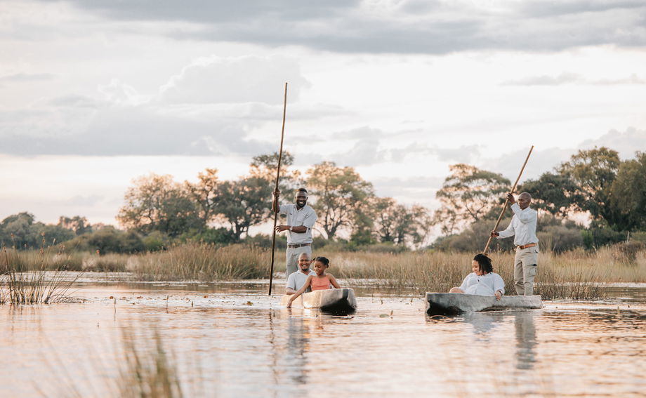 guests and guides in mokoros floating on delta at Vumbura Plains Camp Wilderness Okavango Delta