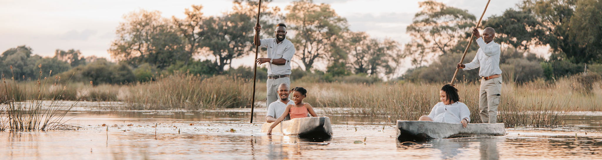 guests and guides in mokoros floating on delta at Vumbura Plains Camp Wilderness Okavango Delta