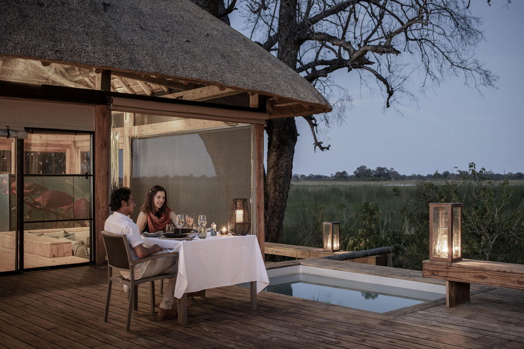 guest sitting at table on deck looking our on planes at Vumbura Plains Camp Wilderness Okavango Delta
