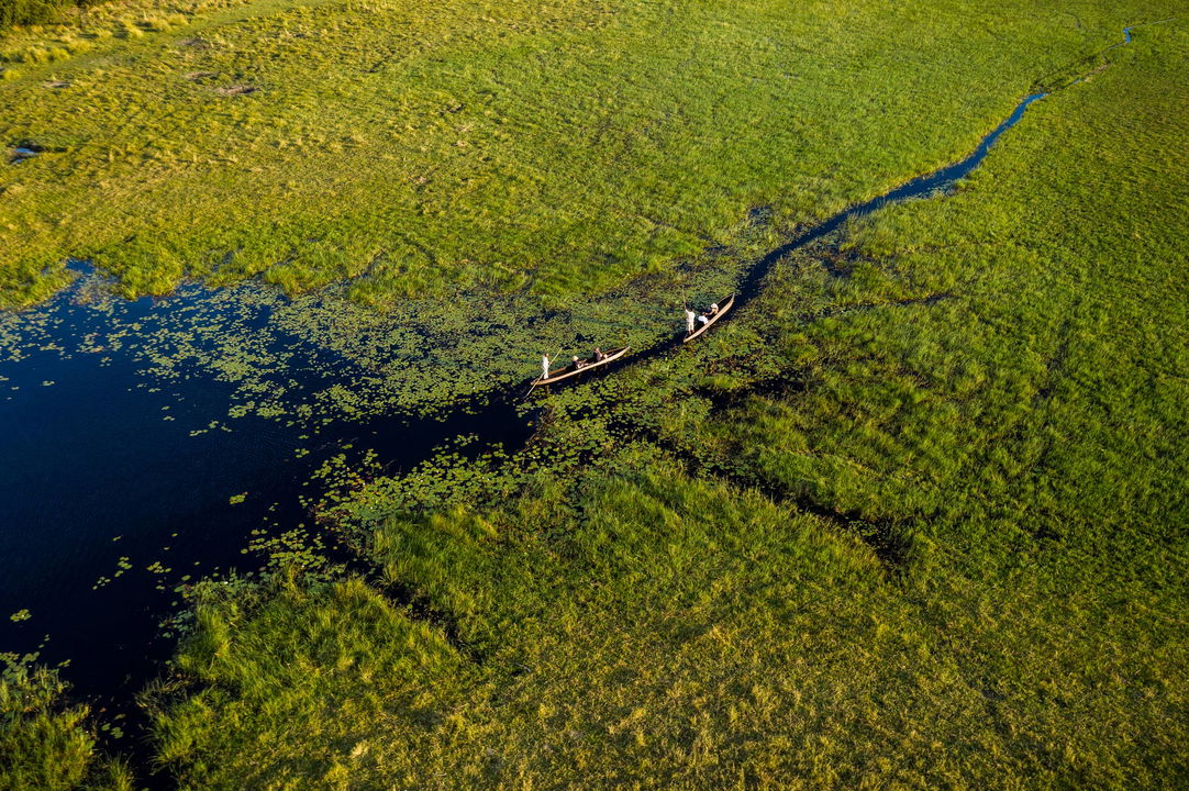 aerial view of two mokoros cruising with guests through waterways on Okavango delta at Xigera Safari Lodge
