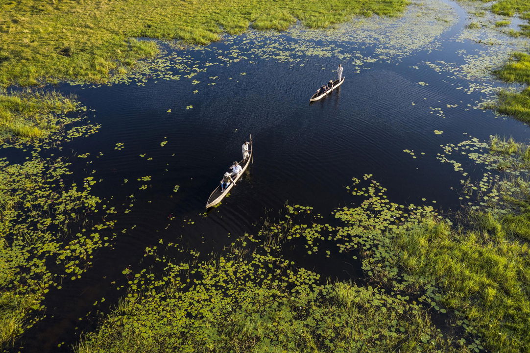 aerial view of two mokoros with guests on the water of the Okavango delta at Xigera lodge