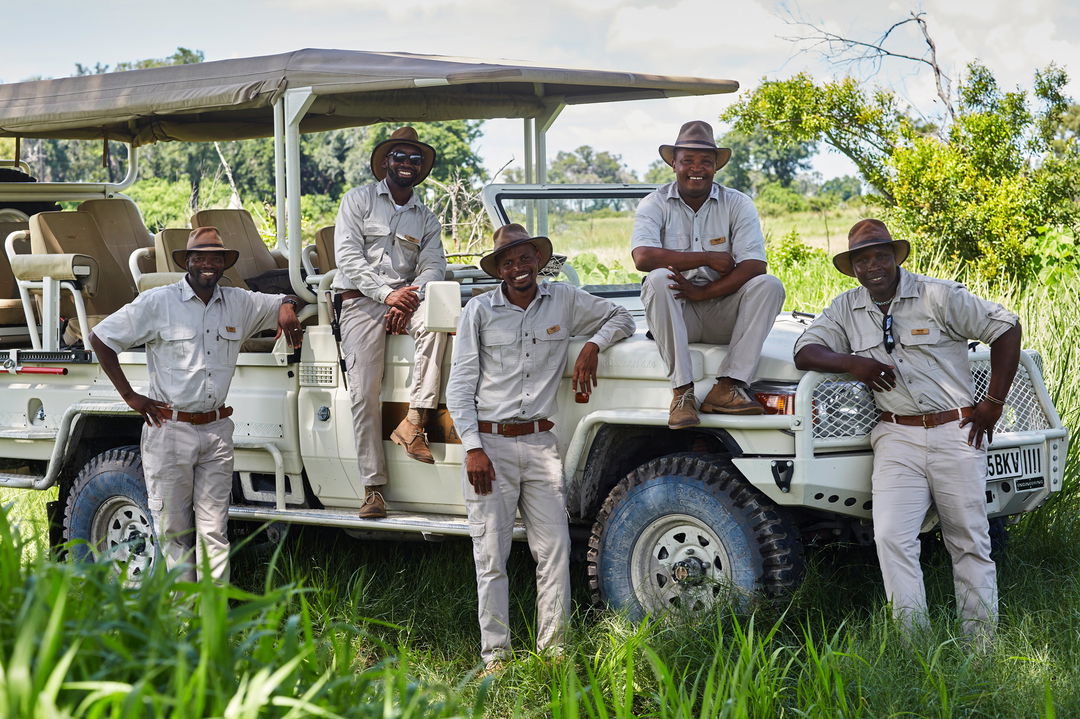 rangers of Xigera Lodge Botswana in front of game drive safari vehicle