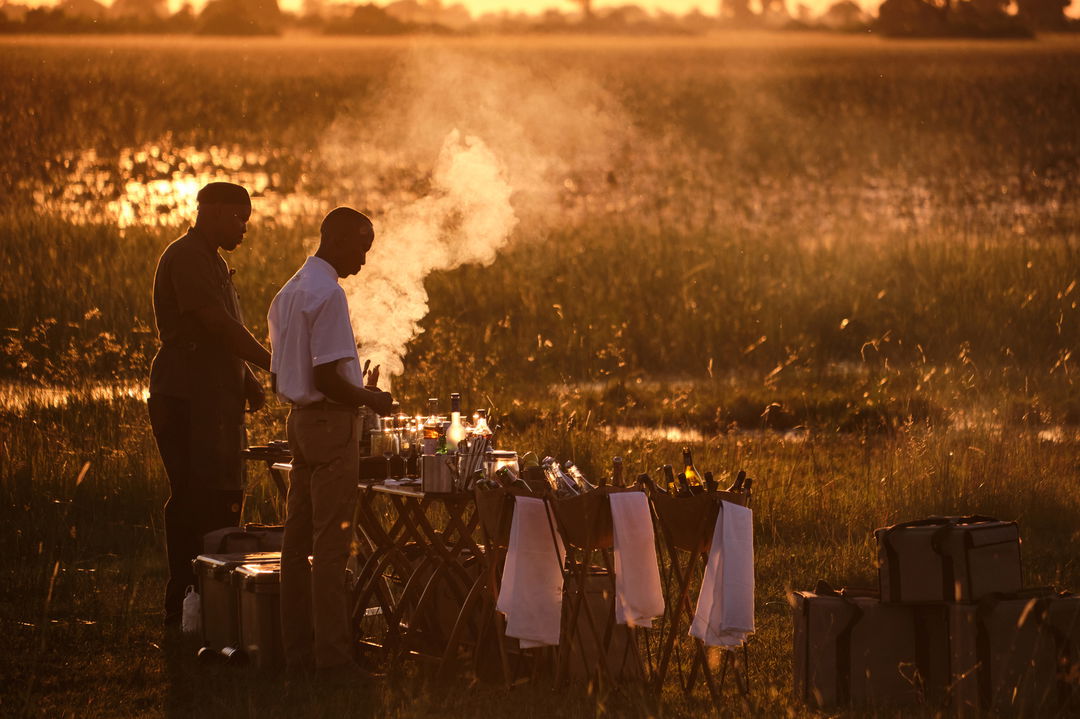 staff preparing for sundowners and snacks in the delta by Xigera Lodge Botswana