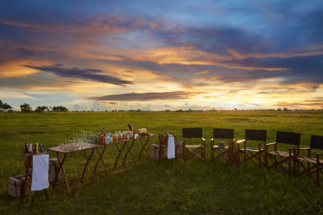 sunset view of tables set for sundowners in the Okavango delta by Xigera Lodge Botswana