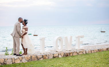 Wedding couple standing on wall at Aguia Negra infront of ocean