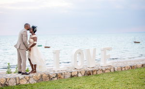 Wedding couple standing on wall at Aguia Negra infront of ocean
