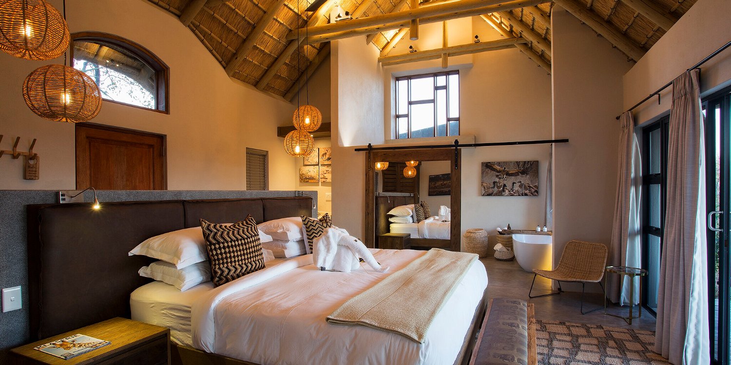 Luxury honeymoon suite king bed with high thatch ceiling at Misava safari camp