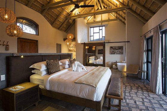 Luxury honeymoon suite king bed with high thatch ceiling at Misava safari camp