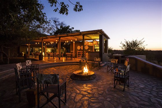 Fire pit seating area or boma at sunset with romantic lighting of the lodge