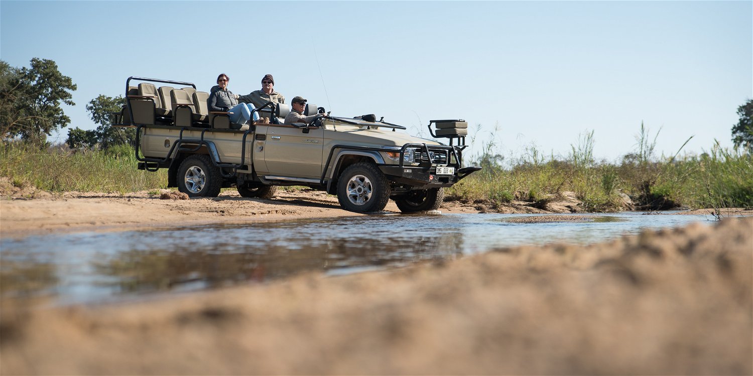 Safari game vehicle crossing Klaserie river with guests