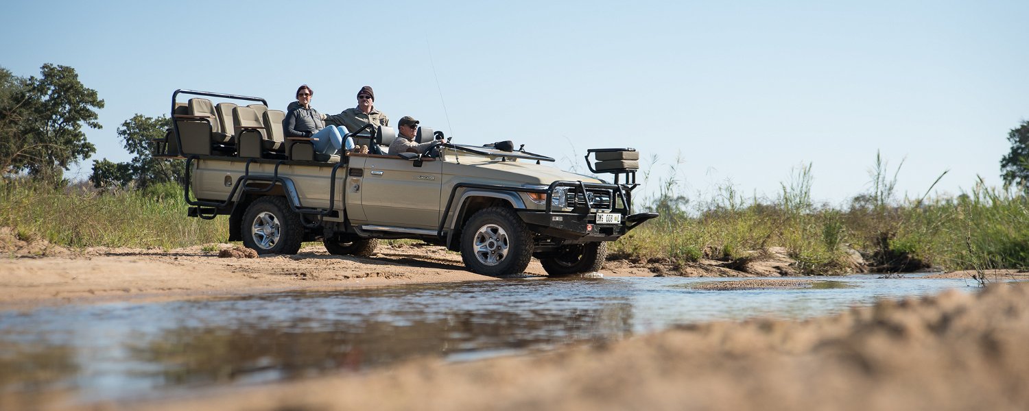 Safari game vehicle crossing Klaserie river with guests