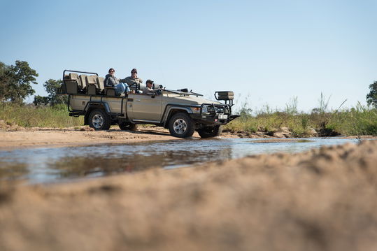 Safari game vehicle crossing Klaserie river with guests